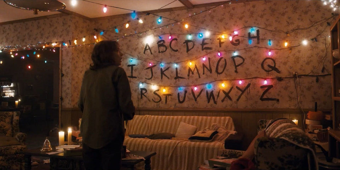 Joyce voor de alfabetmuur met haar brandende lichtslingers in Stranger Things