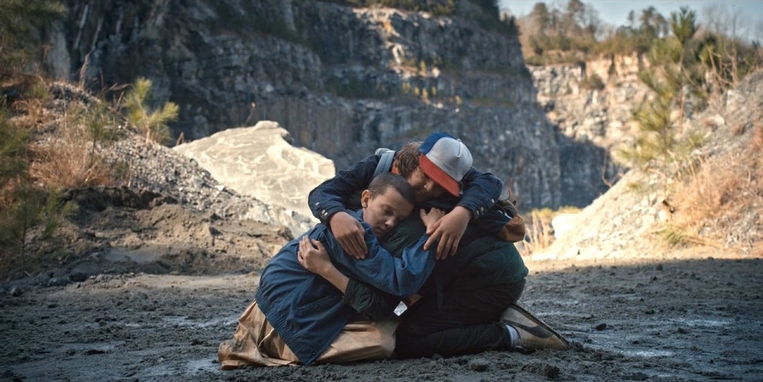 Drie jongens knielen omarmd op de bodem van een steengroeve, Stranger Things seizoen 1 aflevering 6