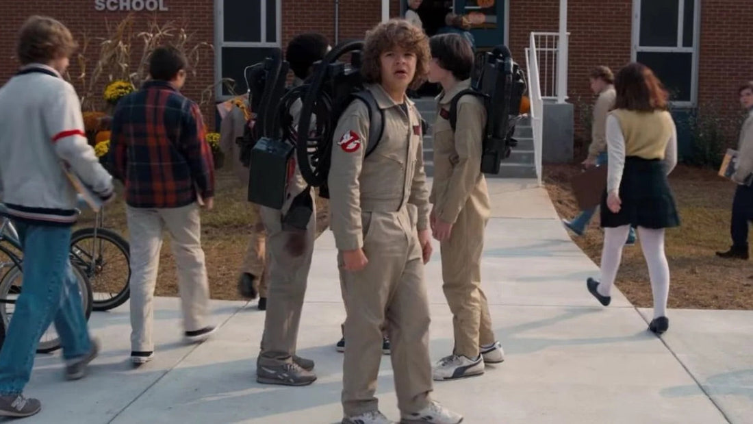 Drie tieners in beige overalls, reservoirs op de rug, voor een bakstenen school