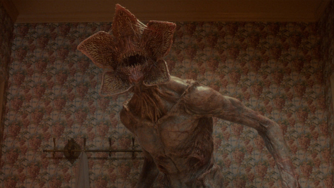 De Demogorgon, met open muil, in een kamer met bloemig behang