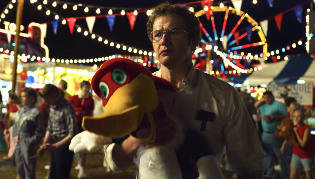 Alexei op de kermis, een pluchen vogel in de armen, het reuzenrad achter hem.