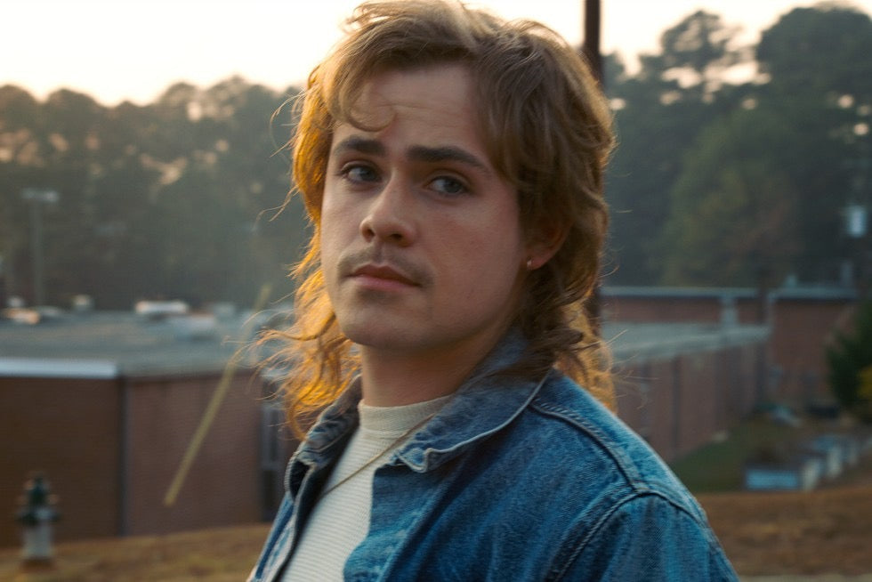 Billy Hargrove, de broer van Max, in een spijkerjas, de blik opzij