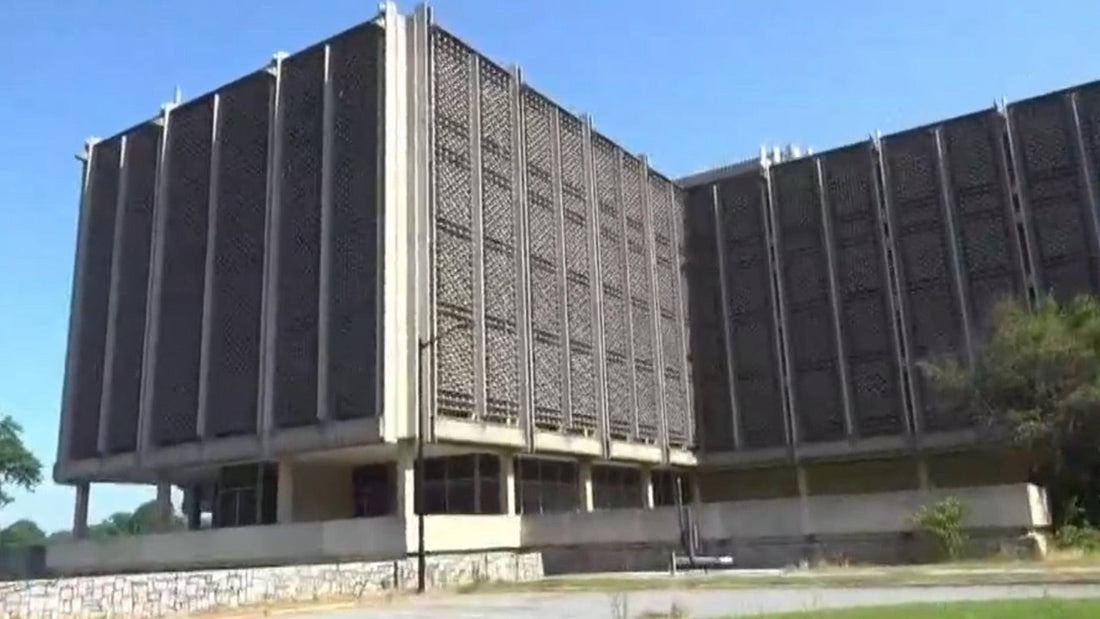 Groot schoolgebouw van beton, vanaf de straat, onder een blauwe hemel.