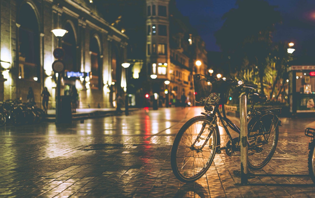 Nachtstraat, lantaarns en fiets, oranje licht op het asfalt