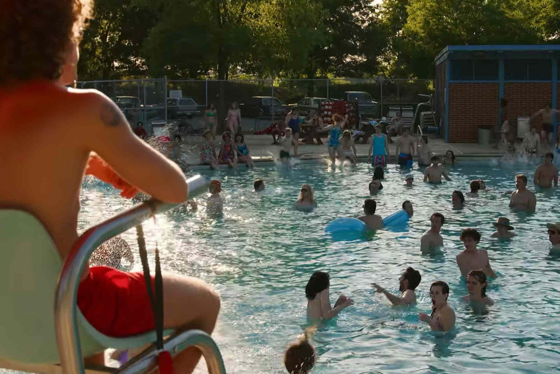 Vol gemeentelijk zwembad in de zomer, met de stoel van de badmeester op de voorgrond.
