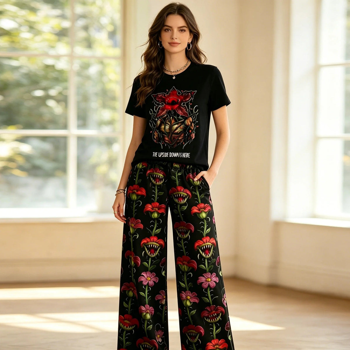 Vrouw in de Stranger Things-pyjama met zwart Demogorgon-T-shirt en wijde bloemenbroek